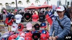 2024年1月7日，在总统大选前一周，一名街头小贩在高雄主要反对党国民党的竞选集会上出售台湾旗帜和帽子。（法新社照片）