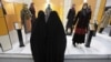 FILE - Head-to-toe veiled Iranian women look at mannequins in a women's dress show in Tehran, Iran, March 3, 2012. 