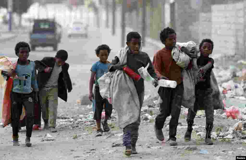Children walk as they collect empty plastic bottles in a street in Sana'a, Yemen.