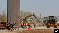 ARCHIVO - Contratistas del gobierno levantan una sección del muro fronterizo financiado por el Pentágono a lo largo del río Colorado, el 10 de septiembre de 2019, en Yuma, Arizona.