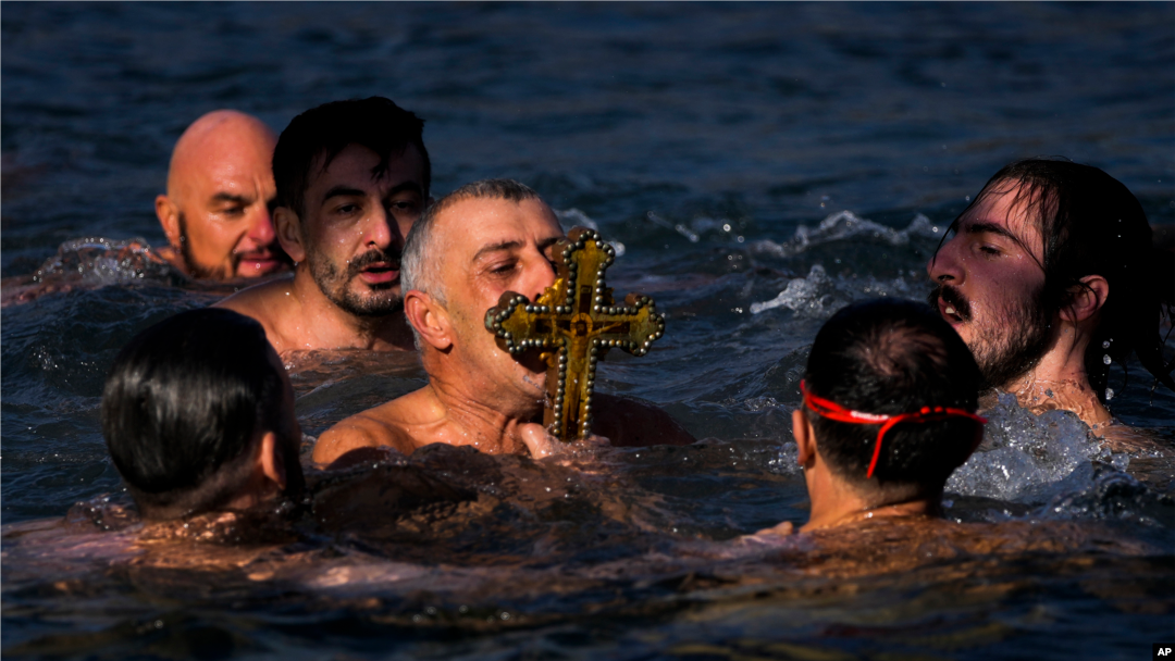 Católicos ortodoxos besan un crucifijo de madera recuperado en el Cuerno de Oro durante la ceremonia de Epifanía en Estambul, Turquía, el jueves 6 de enero de 2022. (Foto AP/Francisco Seco)