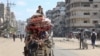 Palestinianos transportam os seus pertences enquanto fogem de áreas a norte da Cidade de Gaza.
