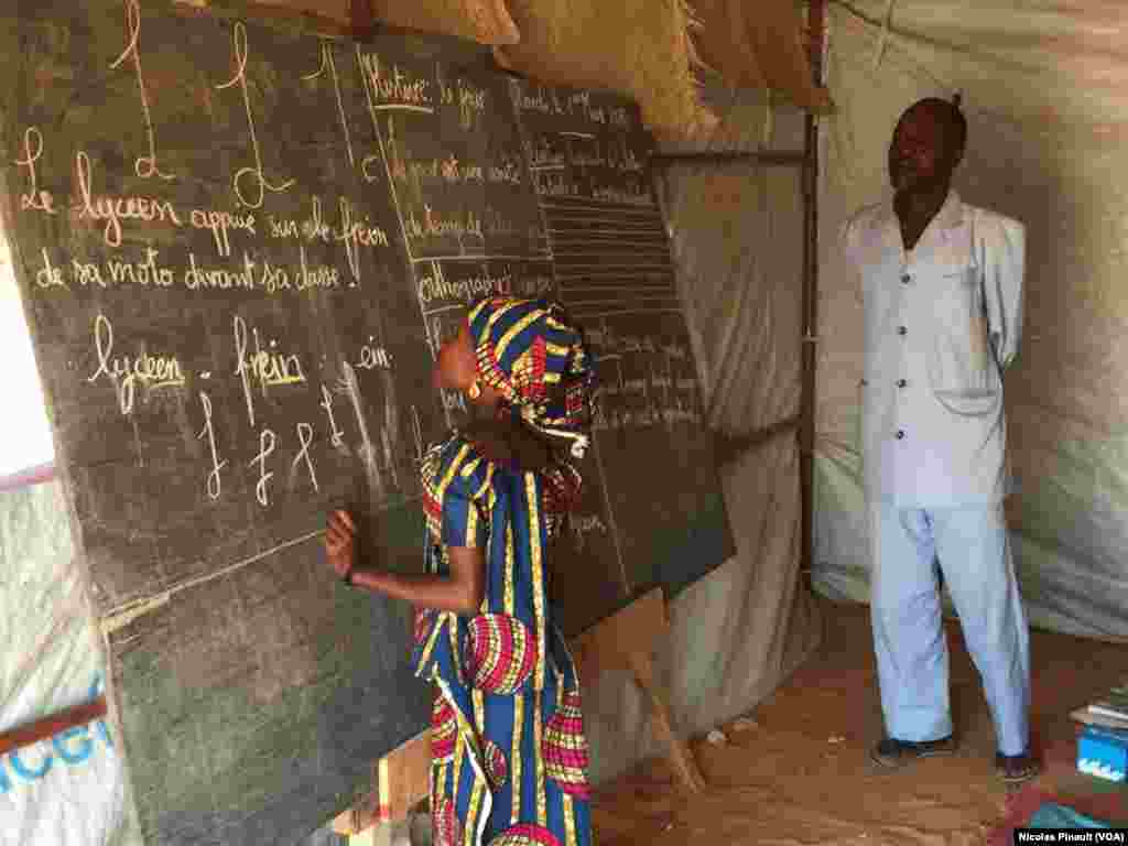 A 10-year-old school girl writes on the chalkboard in a temporary classroom at Ngourtoua camp, near Diffa, Niger, March 1, 2016. (N. Pinault/VOA)
