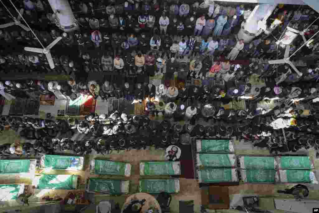 Palestinians pray by the bodies of 15 members of the Izzedine al-Qassam Brigades, the military wing of Hamas, who were killed in Israeli bombardment of the Gaza Strip, in Khan Younis.