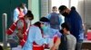 FILE - Health care workers receive a COVID-19 vaccination at Ritchie Valens Recreation Center, Jan. 13, 2021, in Pacoima, Calif. 