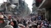 FILE - This picture taken on Jan. 31, 2014, and released by the UNRWA, shows residents of the besieged Palestinian camp of Yarmouk, queuing to receive food supplies, in Damascus, Syria. 
