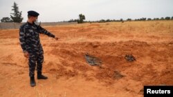 Mwanajeshi wa jeshi la utawala wa Libya unaotambulika kimataifa akionyesha makaburi ya pamoja yaliogunduliwa Tarhouna , Libya, Juni 11, 2020.