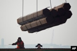 在中国唐山曹妃甸港口，工人把钢管装船。（2012年2月20日）中国钢铁产品受到欧盟制裁