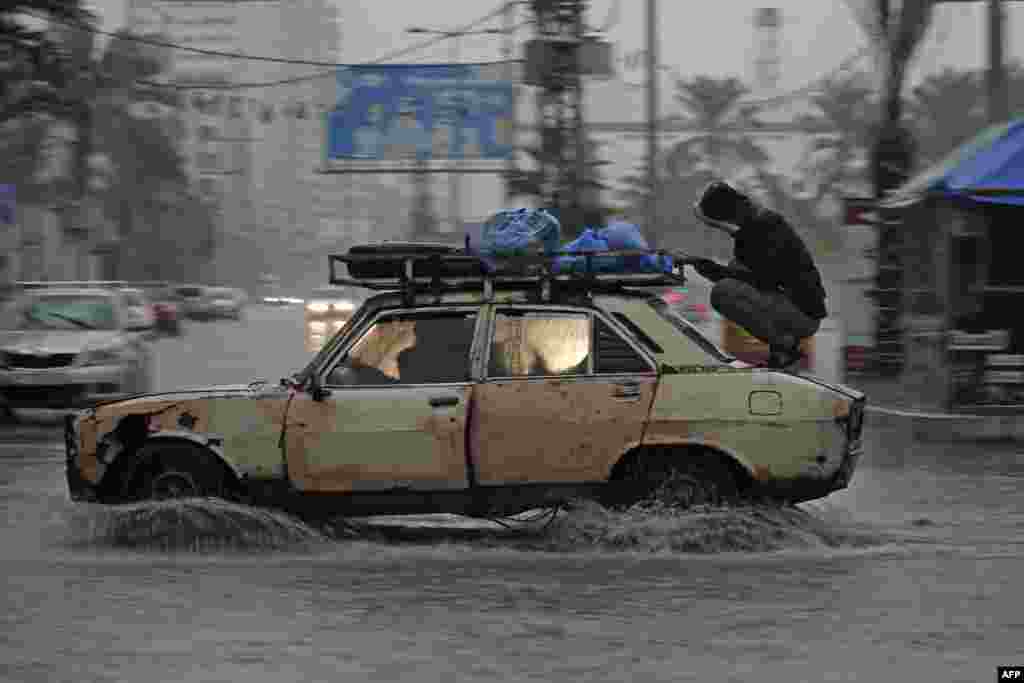 A car drives through a flooded road following heavy rain in Gaza City.