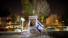 FILE - An Israeli peace activist hands out signs prior to a protest in Tel Aviv, Israel, Jan. 15, 2011. A newly-proposed Israeli law would require nonprofit groups to wear badges identifying foreign sources of funding.