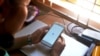 FILE - A woman uses her mobile phone to access Facebook in Naypyidaw, March 16, 2021, as Myanmar authorities ordered telecommunications companies to restrict their services on mobile data networks, following the Feb. 1 military coup.