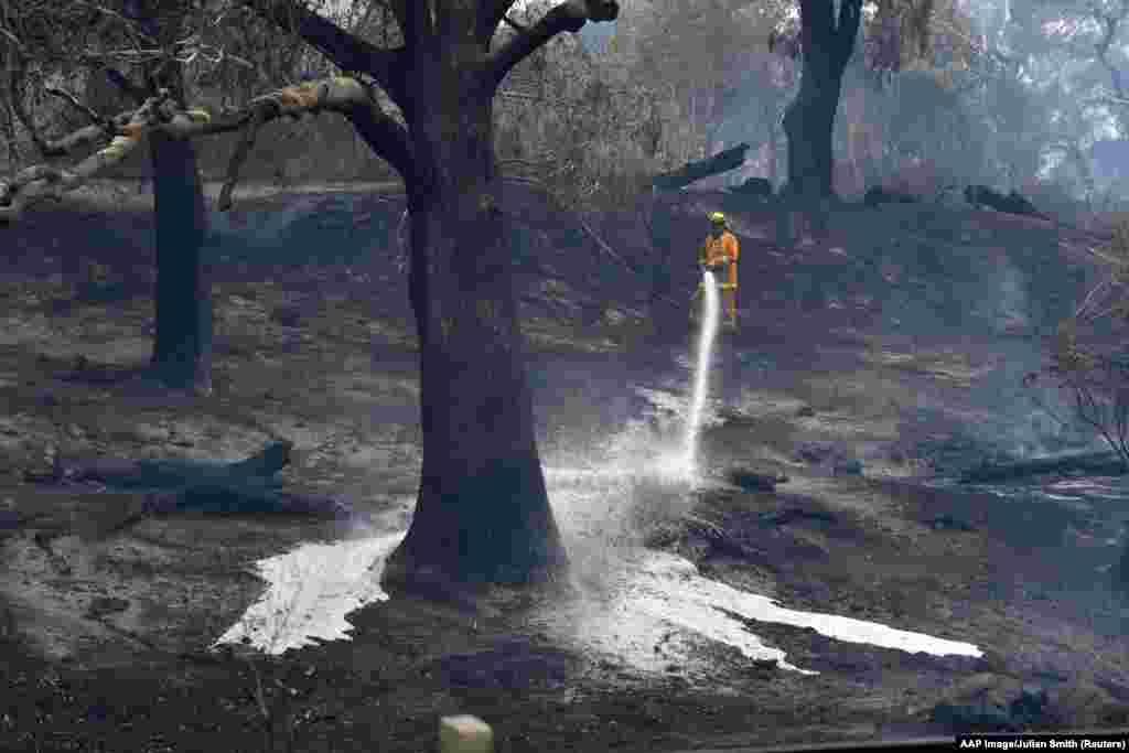 A CFA firefighter sprays water after a fire impacted Clovemont Way, Bundoora in Melbourne, Australia.