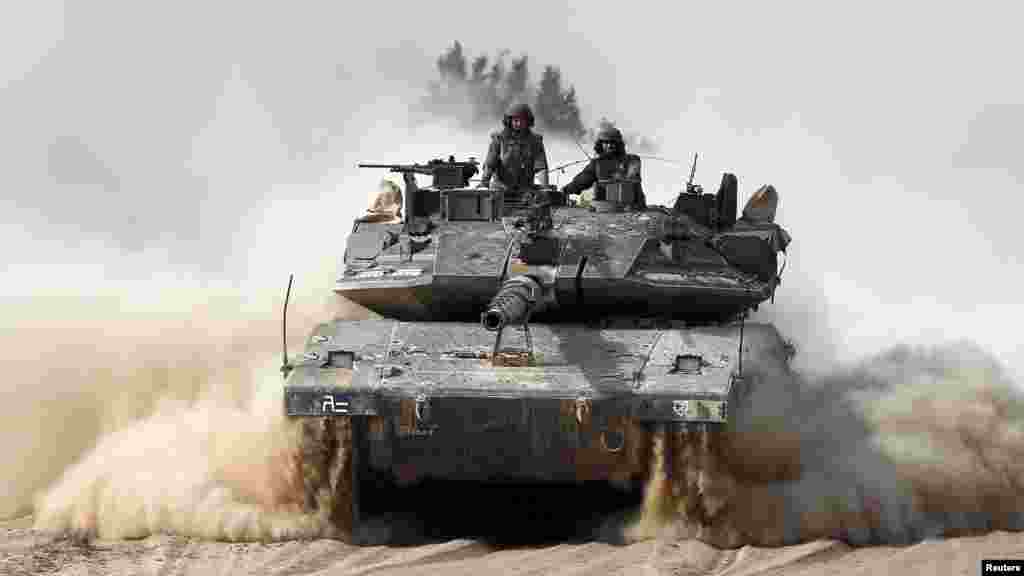 Israeli soldiers ride atop a tank outside the southern Gaza Strip, July 7, 2014.