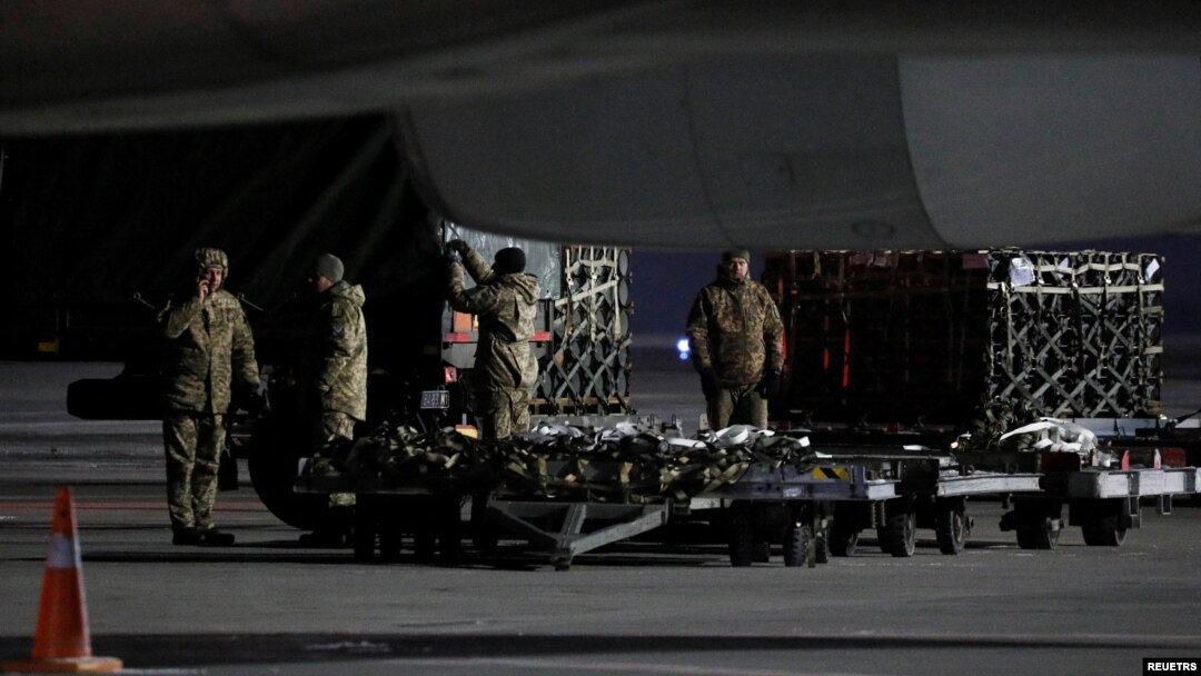 Miembros de los servicios ucranianos descargan un envío de ayuda militar entregada como parte de la asistencia de seguridad de EE. UU. a Ucrania, en el Aeropuerto Internacional de Boryspil en las afueras de Kiev, Ucrania, el 25 de enero de 2022. 