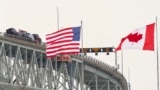 The US and Canadian flags fly on the US side of the St. Clair River near the Bluewater Bridge border crossing between Sarnia, Ontario and Port Huron, Michigan on January 29, 2025.