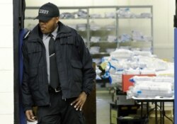 FILE - A Milwaukee County sheriff guards a room where ballots are stacked up as a statewide presidential election recount begins, Dec. 1, 2016, in Milwaukee.