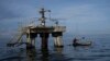 ARCHIVO - Un pescador navega cerca de una instalación petrolera en el Lago de Maracaibo, en el occidente de Venezuela, el 12 de octubre de 2022.