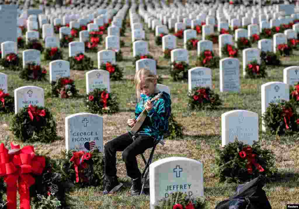 Armando Martin, 11, of California, plays a guitar to honor GYSGT George Figone Jr. in Section 60 at Arlington National Cemetery in Arlington, Virginia, Dec. 25, 2019.