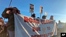 Demonstrators gather to block a road at the base of Hawaii's tallest mountain, Monday, July 15, 2019, in Mauna Kea, Hawaii, to protest the construction of a giant telescope on land that some Native Hawaiians consider sacred. 