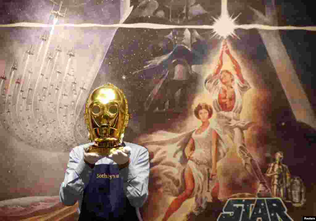 A Sotheby's employee poses with a "Return of the Jedi" promotional C-3PO Helmet 1983, estimated at £15,000-£25,000 created by George Lucas' visual effects company, during a photocall at Sotheby's in London, Britain.