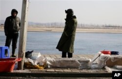 中国渔民在丹东的河边卖鱼，河对岸是朝鲜边境城镇新义州。中国东北受朝鲜之害(2013年2月7日)