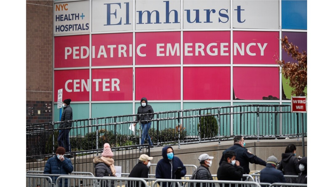 FILE - In this March 25, 2020, file photo, a woman exits a new coronavirus testing site while others wait in line at Elmhurst Hospital Center, in the Queens borough of New York.