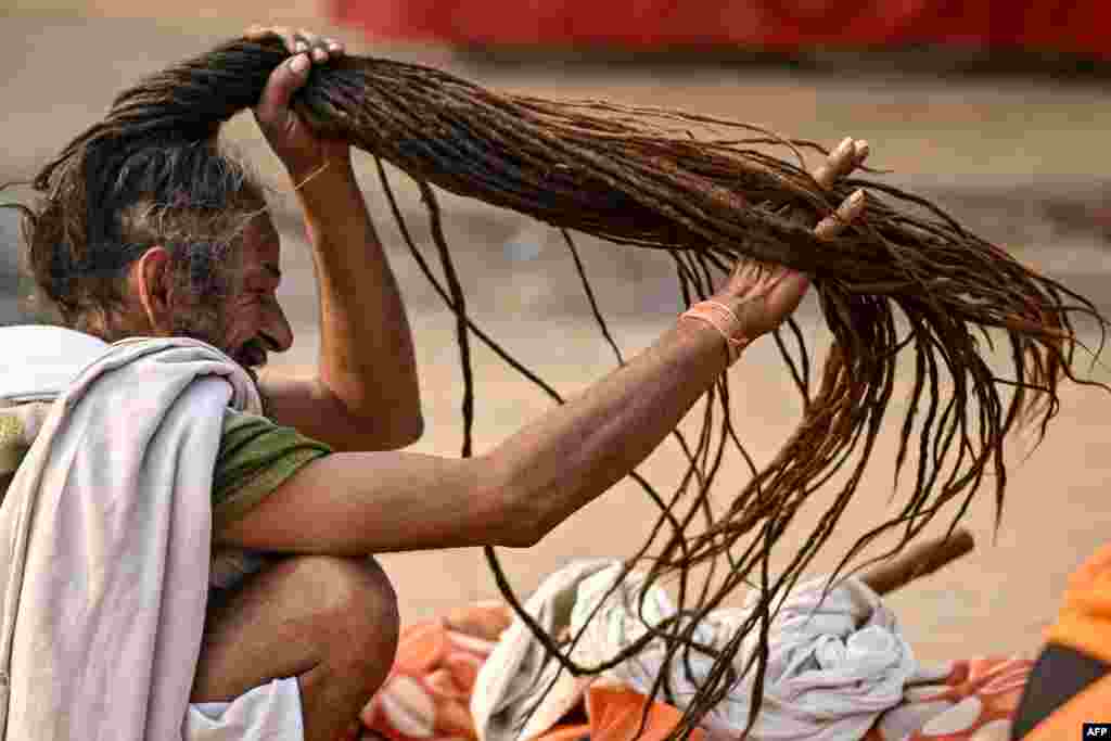 A Hindu holy man braids his hair after taking a holy dip in the sacred waters of the Sangam, the confluence of the Ganges, Yamuna and mythical Saraswati rivers, during the Maha Kumbh Mela festival in the Indian city of Prayagraj.