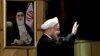 Iranian President Hassan Rouhani waves as he stands next to a portrait of Iran's Supreme Leader Ayatollah Ali Khamenei, after he registered for February's election of the Assembly of Experts, the clerical body that chooses the supreme leader, at Interior 