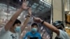 FILE - Protesters, center and left, are detained by a police officer in a shopping mall in during a pro-democracy protest against Beijing's national security law, in Hong Kong, July 21, 2020.