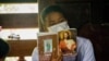 FILE - A Karen woman holds up a hymn book during Christian mass gathering, Umphang, Thailand, May 23, 2021.
