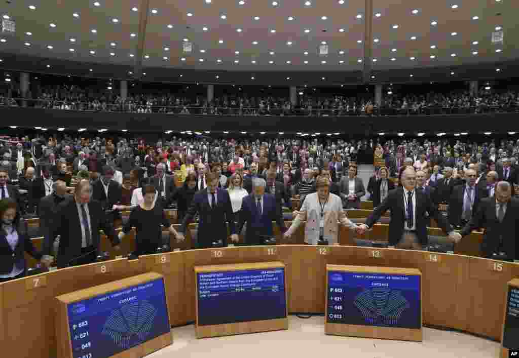 MEP's sing and hold hands after a vote on the UK's withdrawal from the EU, the final legislative step in the Brexit proceedings, during the plenary session at the European Parliament in Brussels, Belgium, Jan. 29, 2020. The U.K. is due to leave the EU on Friday, Jan. 31, 2020, the first nation in the bloc to do so.