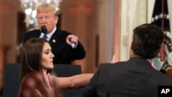 As President Donald Trump points to CNN's Jim Acosta, a White House aide tries to take the microphone from him during a news conference in the East Room of the White House, Nov. 7, 2018, in Washington. 