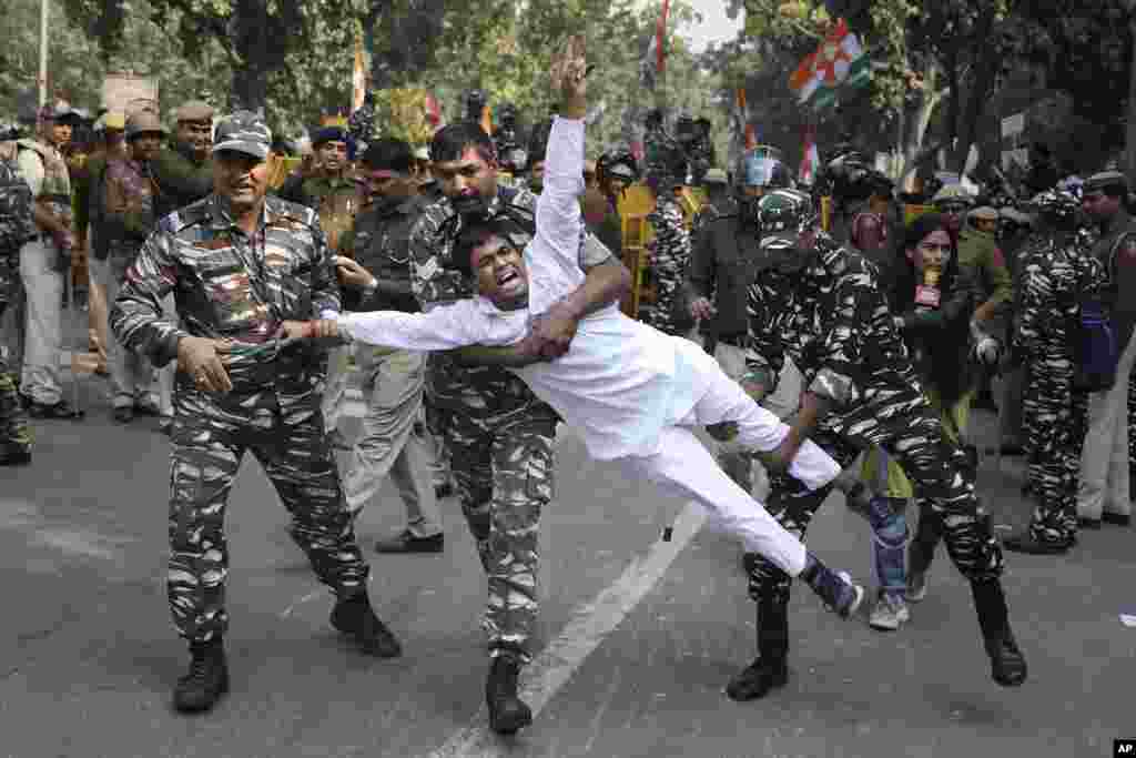 Paramilitary soldiers detain a Congress party supporter during a protest against the withdrawal of Special Protection Group (SPG) cover to party president Sonia Gandhi, her immediate family members and former Prime Minister Manmohan Singh, in New Delhi, India.