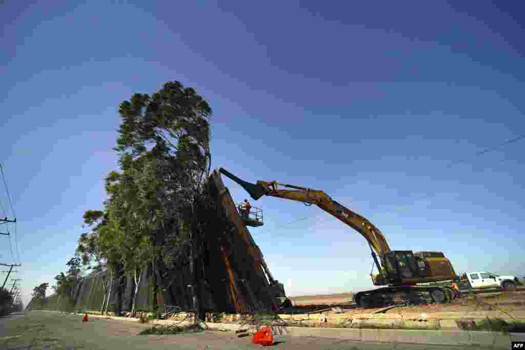 A construction crew works on a fallen section of the U.S.-Mexico border wall as seen from Mexicali, Baja California state, Mexico, Jan. 29, 2020. Newly installed panels from the U.S. border wall in Calexico, California, fell over in high winds, landing on trees on the Mexican side of the border.
