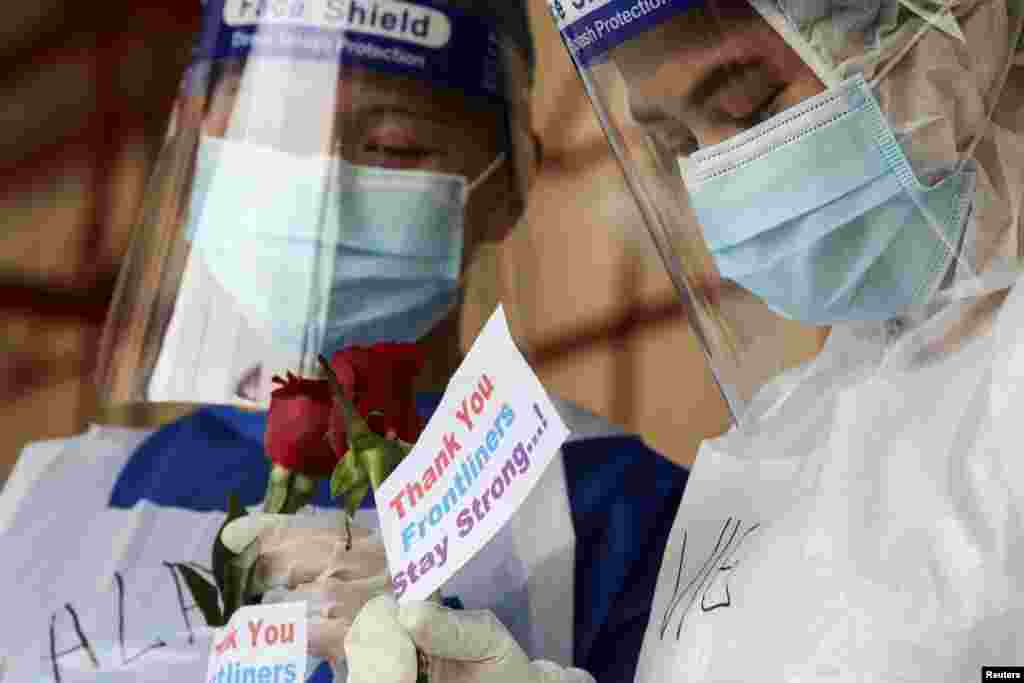 Para petugas medis memegang mawar yang diberikan oleh anggota masyarakat sebagai tanda terima kasih di pusat pengujian Covid-19 di Petaling Jaya, Malaysia 25 Januari 2021. (Foto: Reuters / Lim Huey Teng)