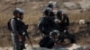 An Israeli border policeman aims his weapon at Palestinians during clashes at the Israeli Hawara checkpoint near the West Bank city of Nablus October 16, 2015. The unrest that has engulfed Jerusalem and the occupied West Bank, the most serious in years, h