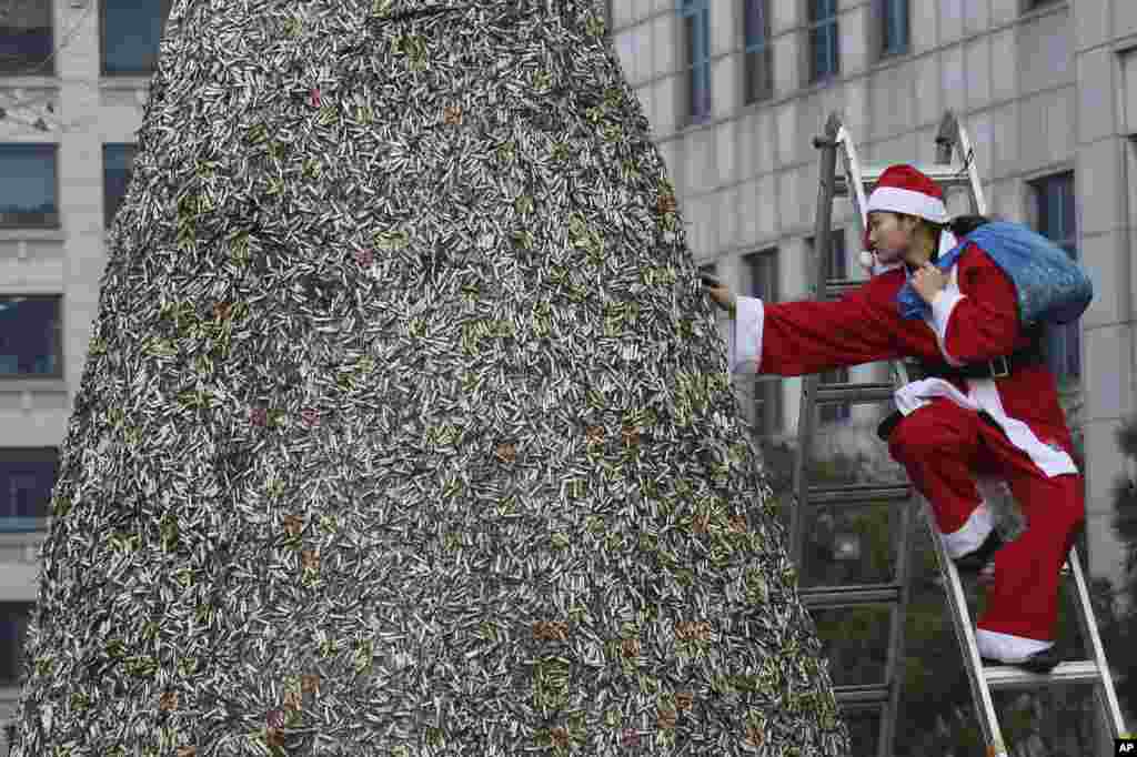 A member of Korean Federation for Environmental Movement in a Santa Claus outfit attaches dumped cigarette butts at a cigarette butt Christmas tree in front of Korea Tobacco & Ginseng Corporation office in Seoul, South Korea.