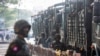 FILE- Soldiers stand next to military vehicles as people gather to protest against the military coup, in Yangon, Myanmar, Feb. 15, 2021.