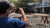 FILE - A journalist and a police officer take pictures of each other as people protest against the military coup in Yangon, Myanmar, Feb. 23, 2021. Journalists reporting on the resistance movement are often forced to work underground or in exile to avoid arrest or retaliation.