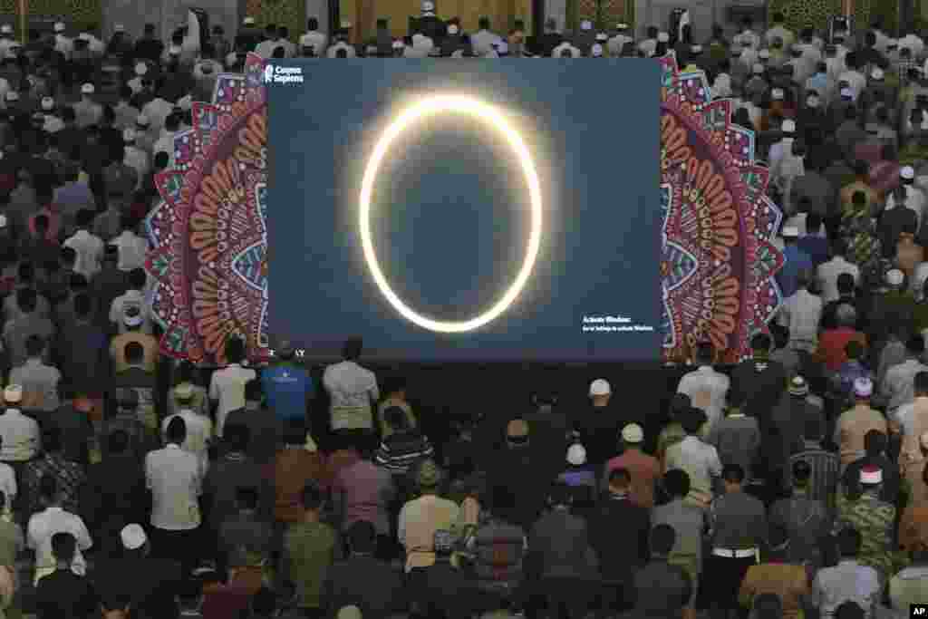Muslim men perform a special 'kusoof' prayer as a live report of the annular solar eclipse is broadcast on a large screen at a mosque in Surabaya, East Java, Indonesia.