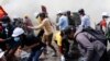 FILE - Tear gas and fire extinguisher gas surround demonstrators as they run away from police during a protest against the military coup in Naypyitaw, Myanmar, March 8, 2021.