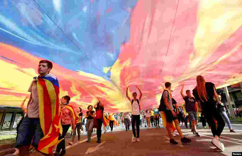Demonstrators walk under an Estelada (Catalan separatist flag) as they march on Diagonal Avenue during Catalonia's general strike in Barcelona, Spain.