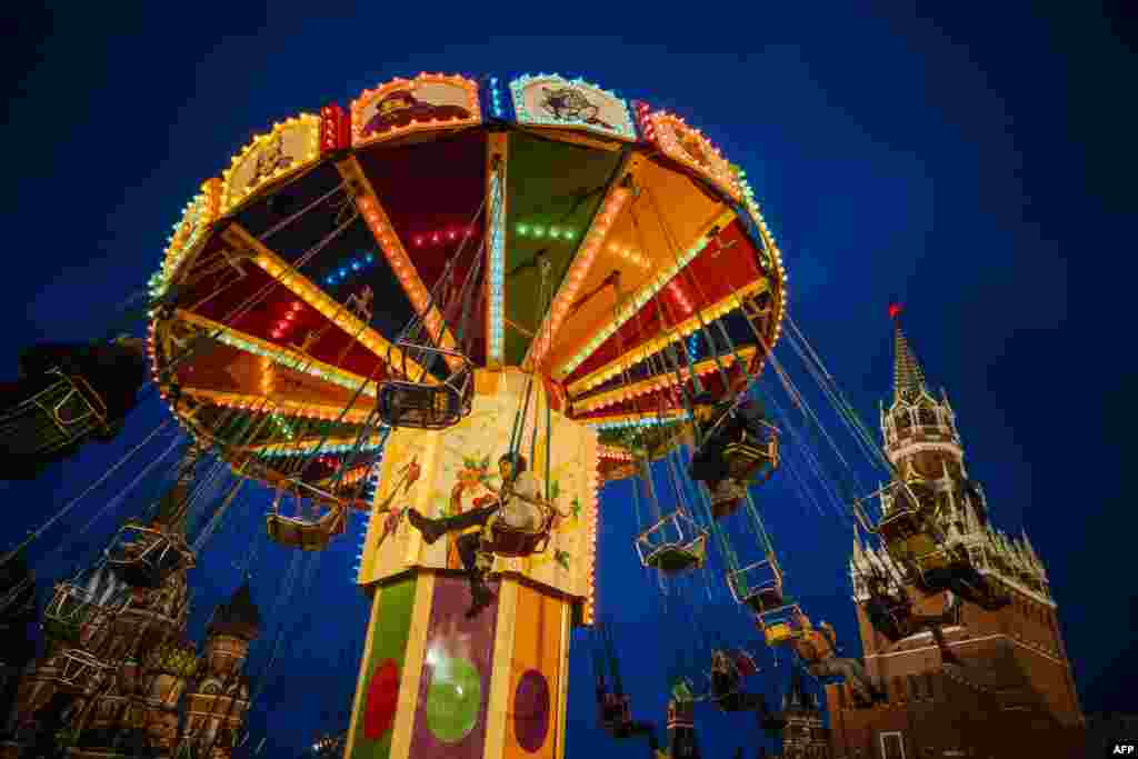People ride a merry-go-round at the Christmas Market at the Red Square in Moscow, as the Kremlin's Spasskaya Tower is seen in the background, Dec. 16, 2019.