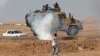 A protester throws stones at an armored army vehicle during a pro-Kurdish demonstration in solidarity with people of Kobani, near the Mursitpinar border crossing on the Turkish-Syrian border, in the Turkish town of Suruc in southeastern Sanliurfa province