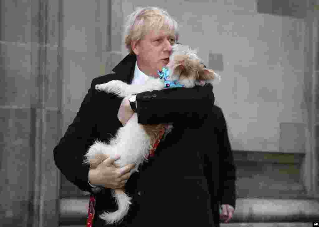 Britain's Prime Minister and Conservative Party leader Boris Johnson holds his dog Dilyn as he leaves after voting in the general election at Methodist Central Hall, Westminster, London.