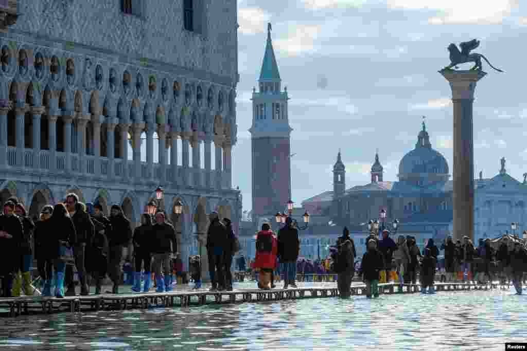 People walk through across a makeshift walkway over the flooded St. Mark's Square in Venice, Italy.