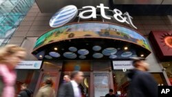 En esta fotografía de archivo del 21 de octubre de 2014, la gente pasa frente a una tienda de AT&T en Times Square de Nueva York.