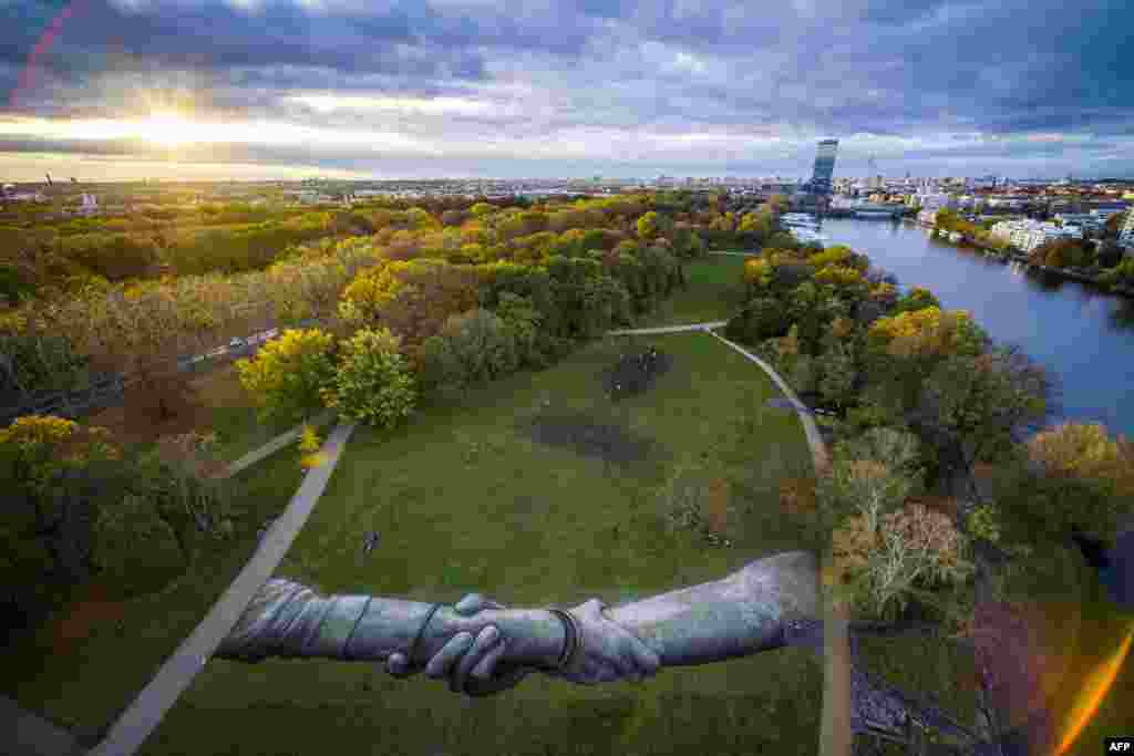 This handout picture released by Saype and Valentin Flauraud shows a giant biodegradable land art painting by French-Swiss artist Saype representing two hands clasped together in the Treptower Park in Berlin, part of his "Beyond Walls" project.