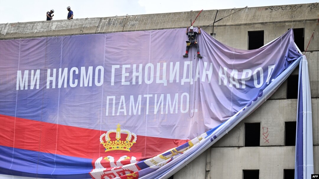 Radnici postavljaju baner sa natpisom "Mi nismo genocidan narod. Pamtimo" u Beogradu (foto: OLIVER BUNIC / AFP)
