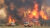 In this image dated Dec. 30, 2019, and provided by NSW Rural Fire Service via their twitter account, firefighters are seen as they try to protect homes around Charmhaven, New South Wales. Wildfires burning across Australia's two most-populous states.